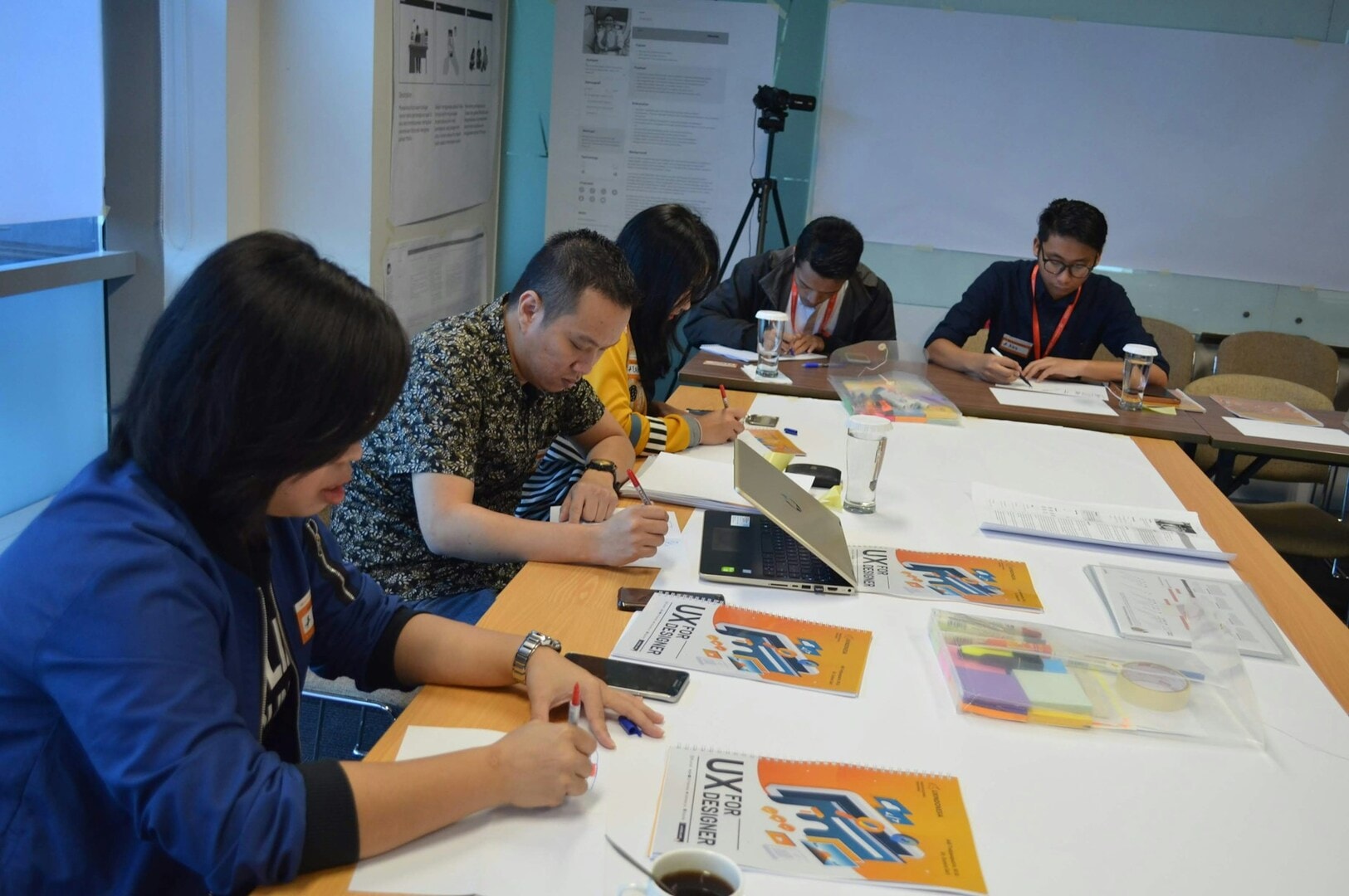 Singapore international students gathered around a table, working together with papers and pens in a study session.