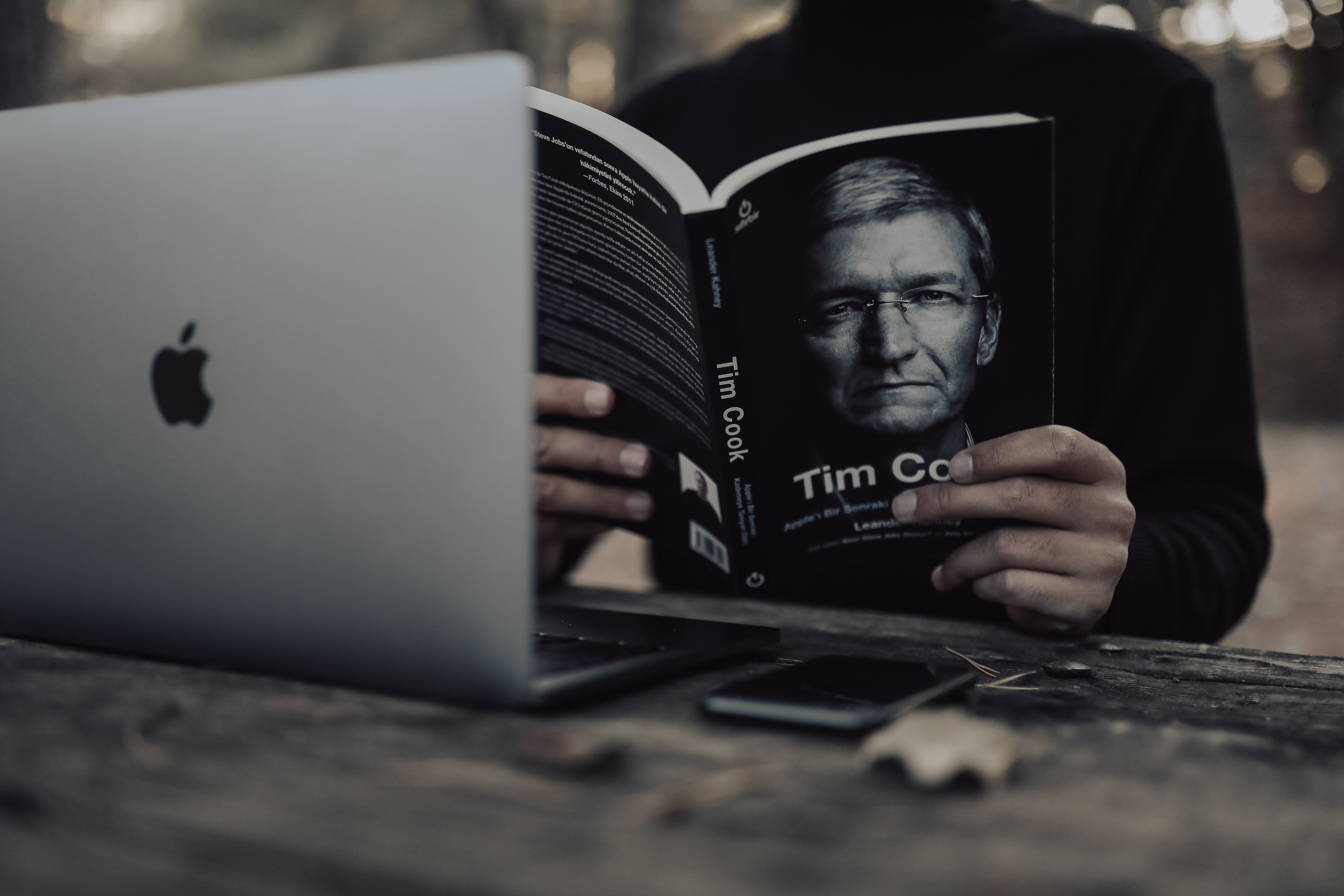 A person reading Apple CEO Tim Cook's biography