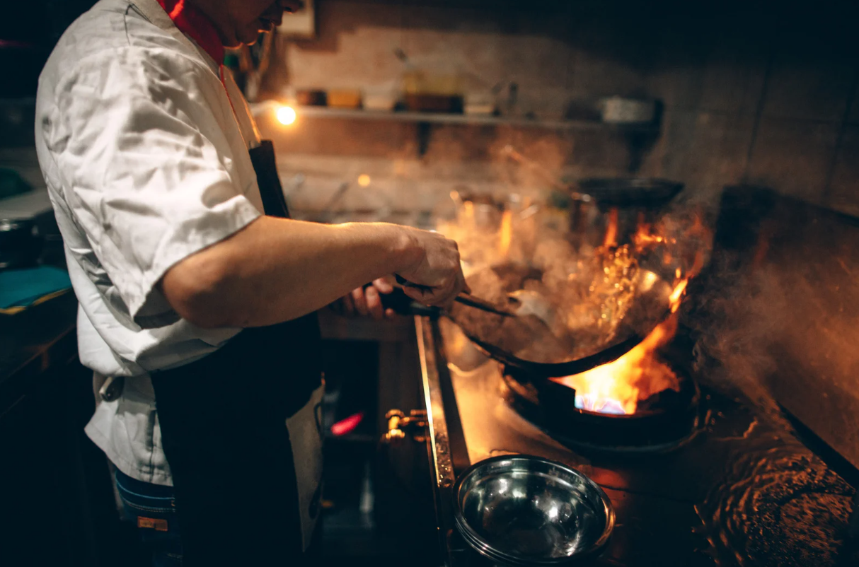 Chef cooking over a hot flaming stove