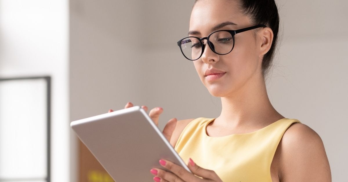 A woman in glasses using a tablet to analyze her net operating profit after tax."