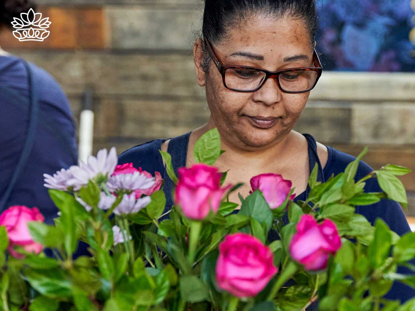 Focused florist arranging a vibrant collection of pink roses and daisies, showcasing the creativity and dedication available at the Fabulous Flowers and Gifts store, inviting customers to browse and shop their hampers.
