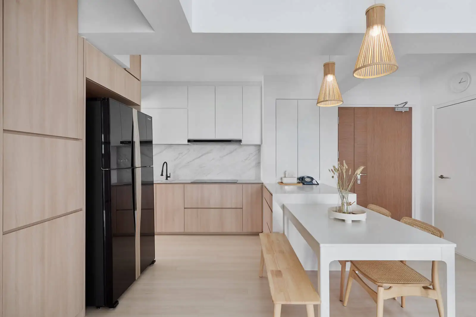 Scandinavian homes interior design – minimalist kitchen-dining space with light oak cabinetry, marble splashback, and woven-seat chairs.