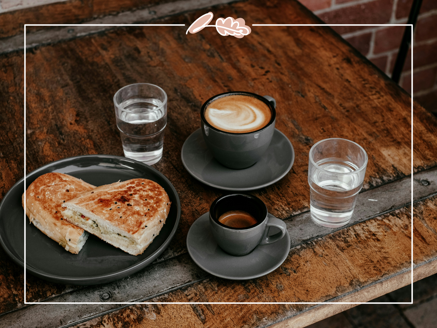 Toasted sandwich with two cups of coffee and two glasses of water on a rustic wooden table. Fabulous Flowers and Gifts