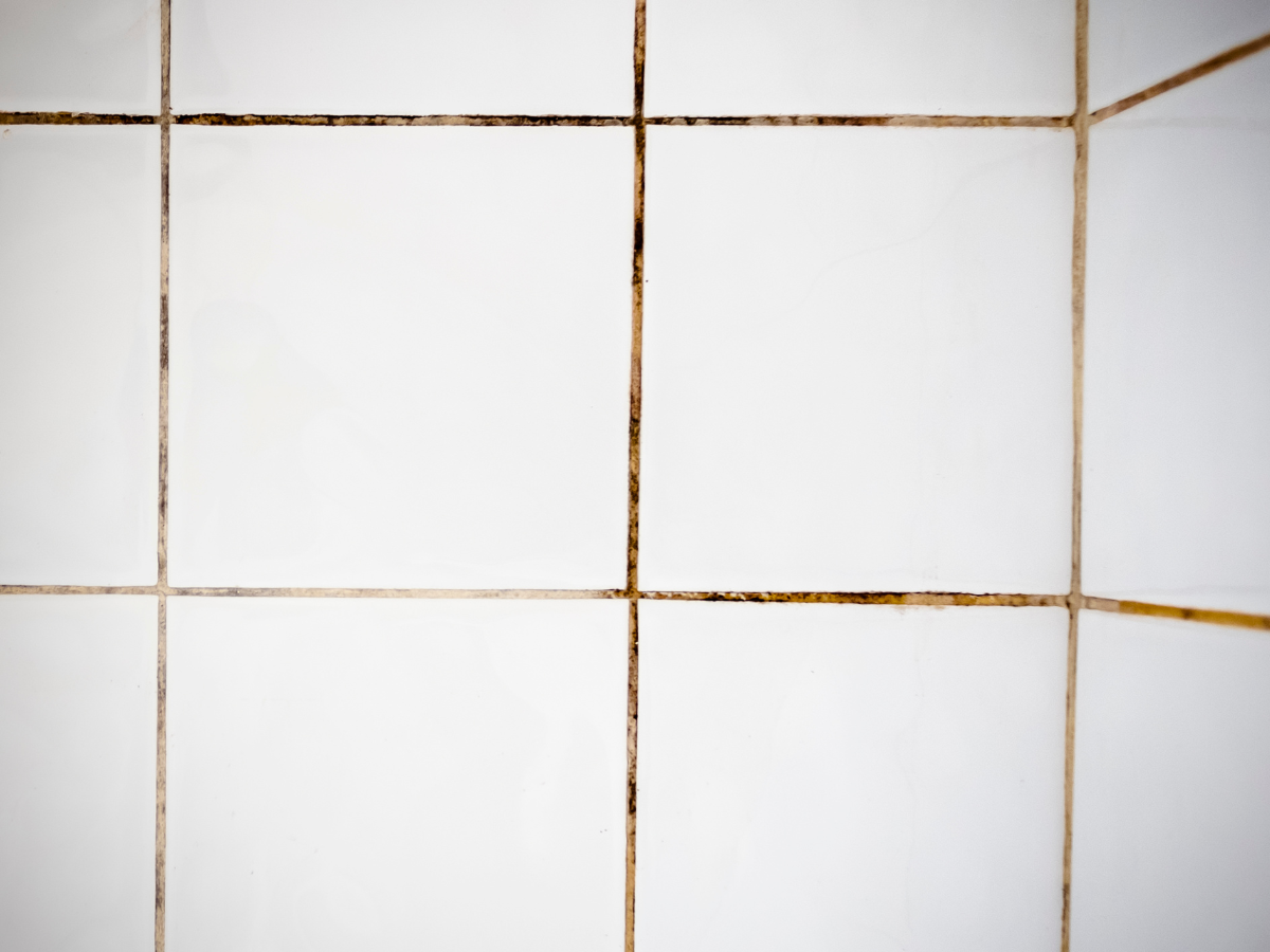 A close-up image of a tile surface with dirty grout lines, highlighting the importance of tile and grout cleaning for maintaining hygiene and aesthetics.