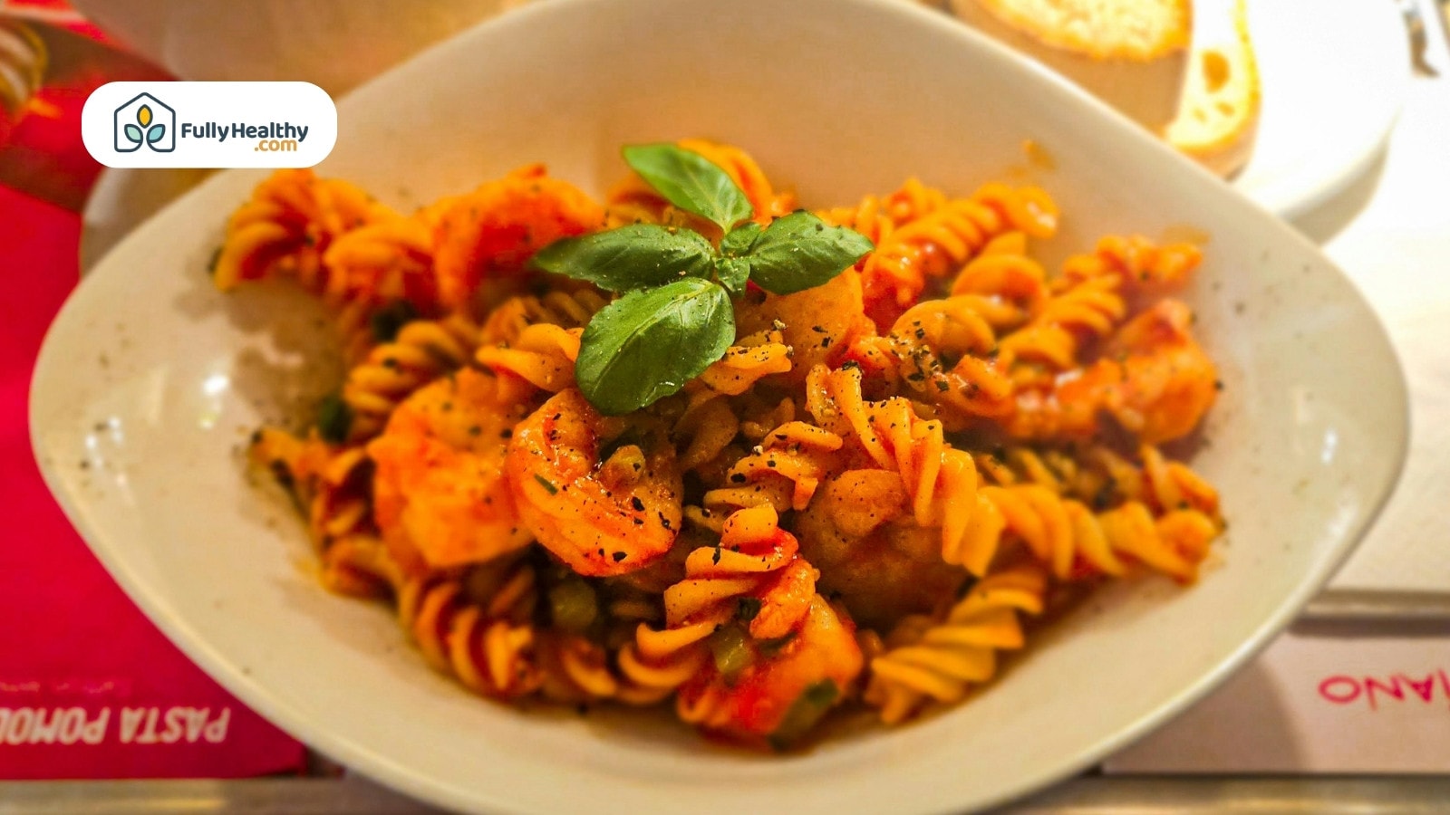 Spiral pasta with shrimp and basil served on white plate