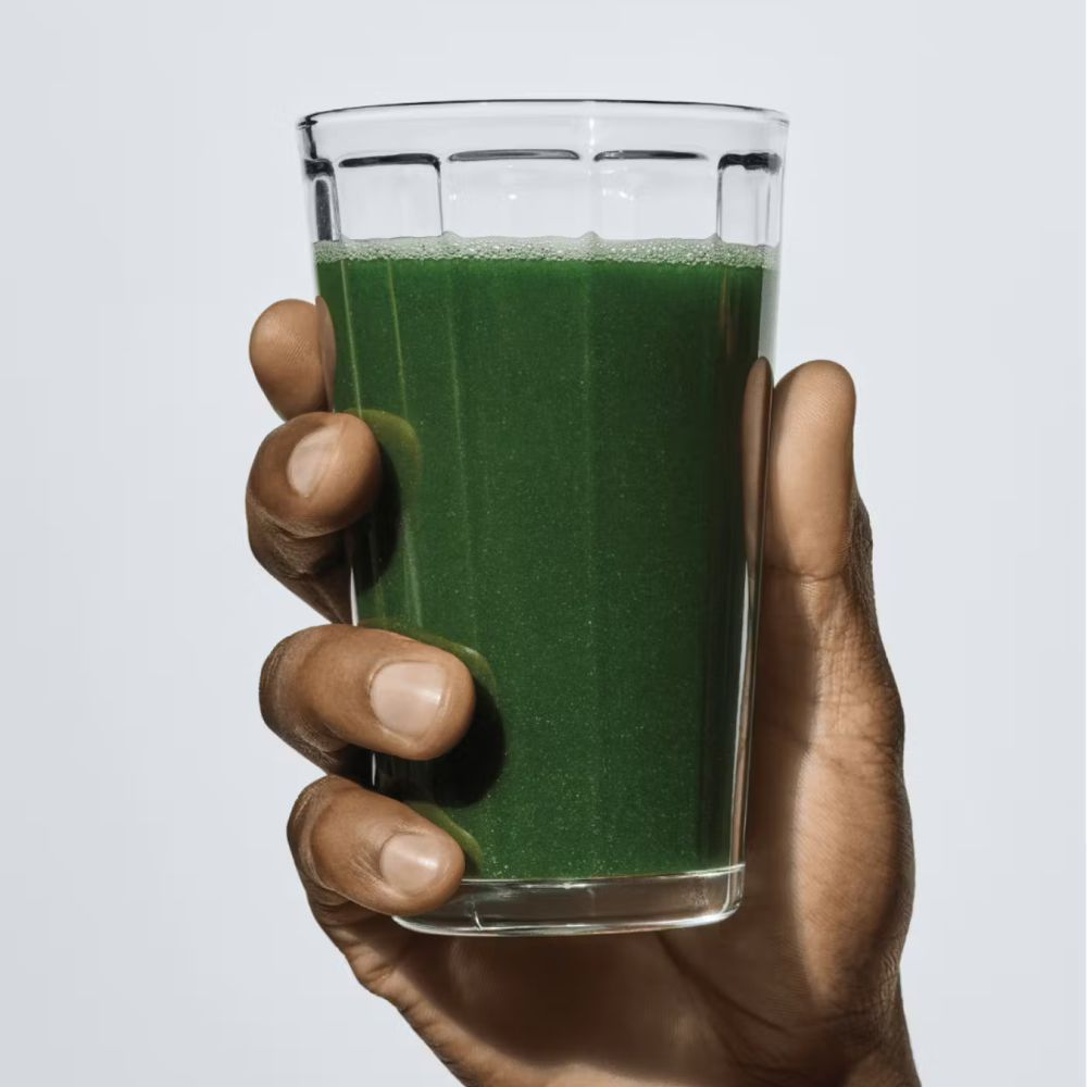 Athletic Greens powder with a scoop and a glass