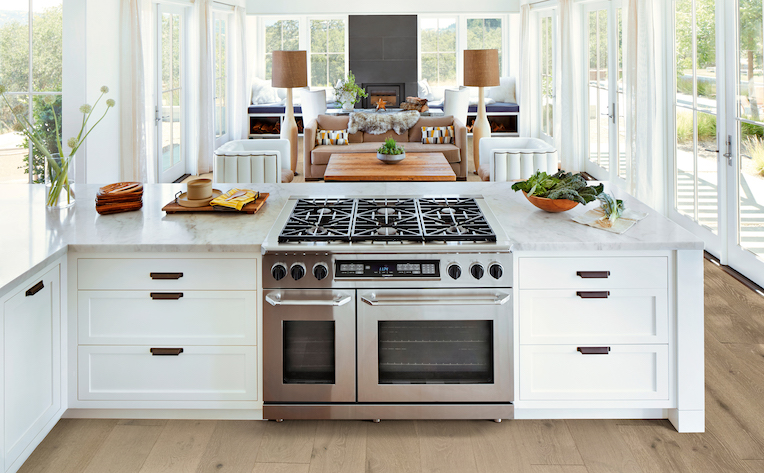 bright open concept kitchen renovation with wood look floors and white cabinet peninsula