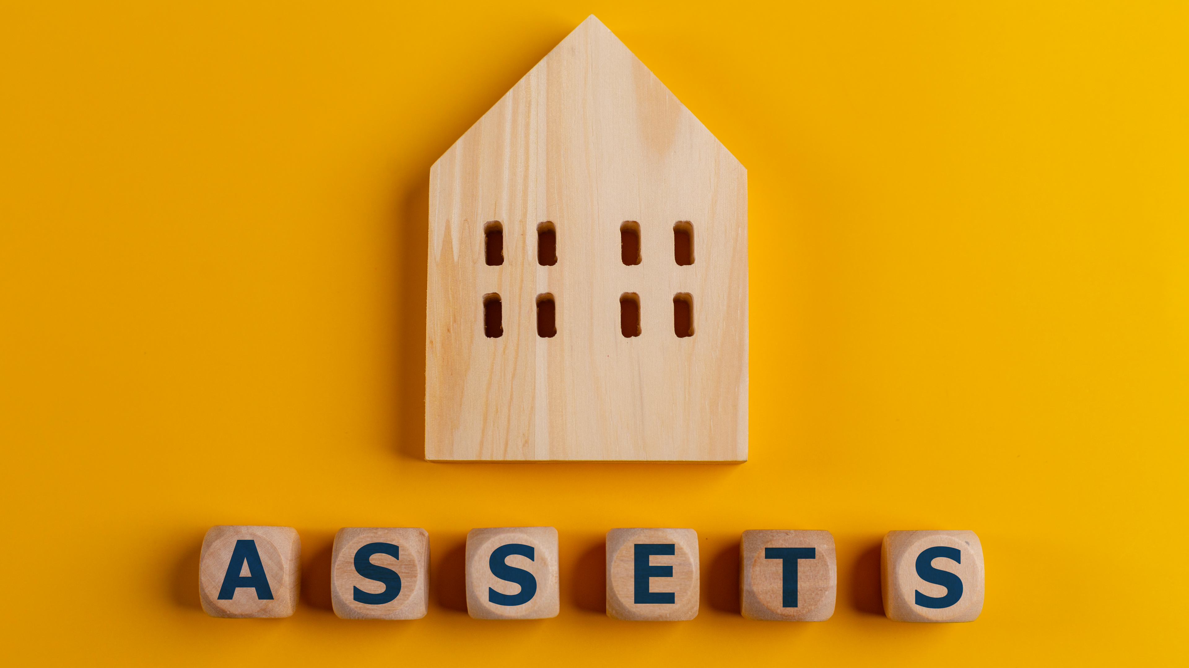"Asset Protection Attorney: Safeguarding your assets, depicted with wooden cubes on a yellow backdrop."