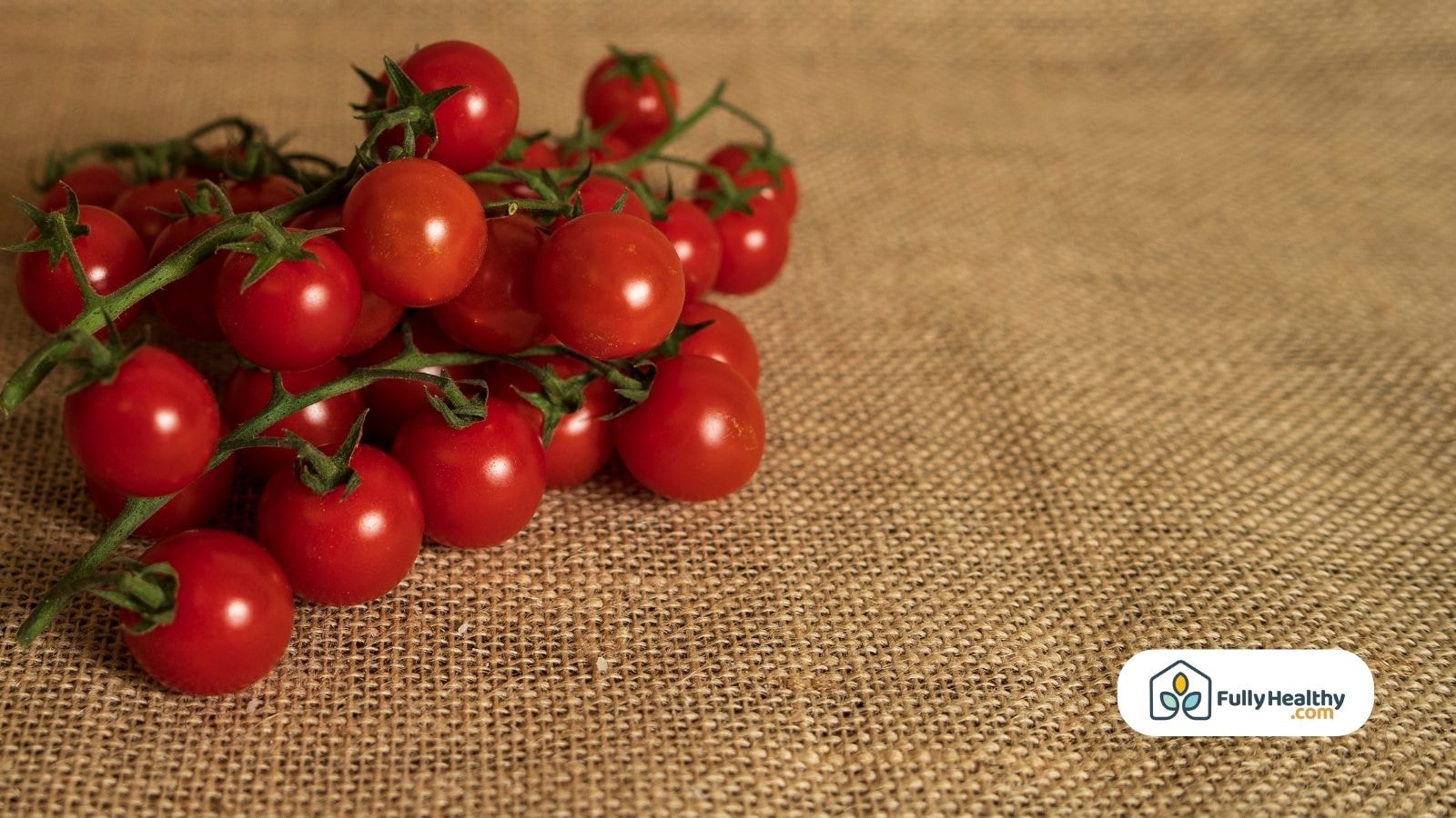 A bunch of fresh cherry tomatoes on rustic burlap fabric background