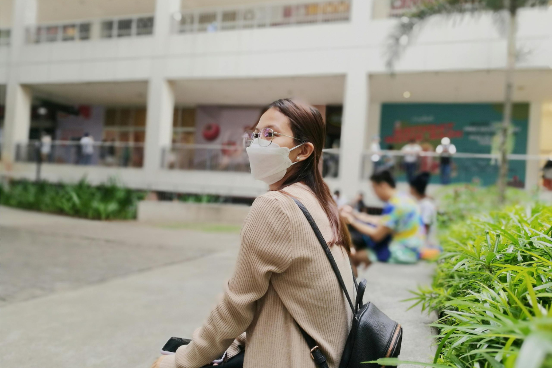 Filipino student wearing a mask while seated in an outdoor school area, reflecting the resilience and adaptability of the Philippine education system during modern challenges.