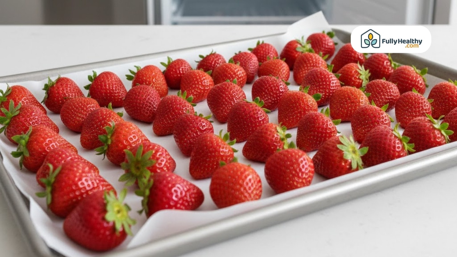 Strawberries spaced on tray lined with parchment paper ready for freezing