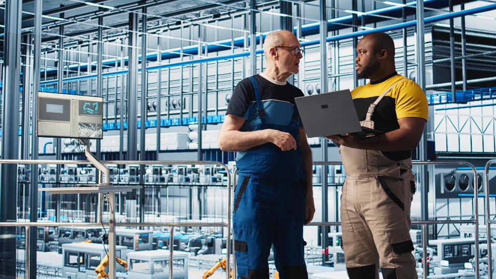 Senior engineer and new trainee using a mobile phone to manage a conference call.