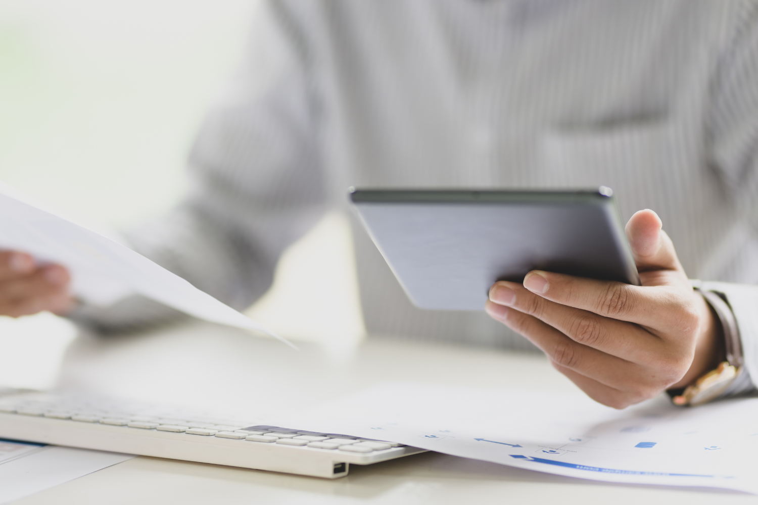 Person holding a tab on his one hand, and a document on another.