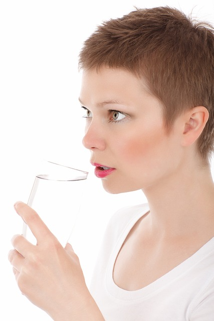 An image of a young woman drinking a glass of water. 