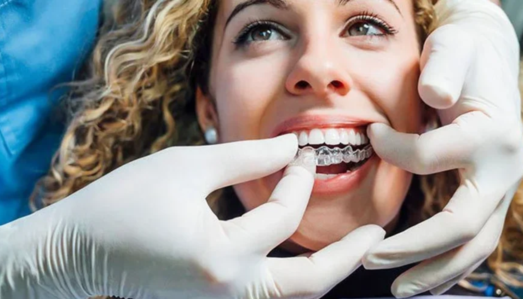 Tannlege setter inn en gjennomsiktig tannregulering på pasientens tenner under behandling.