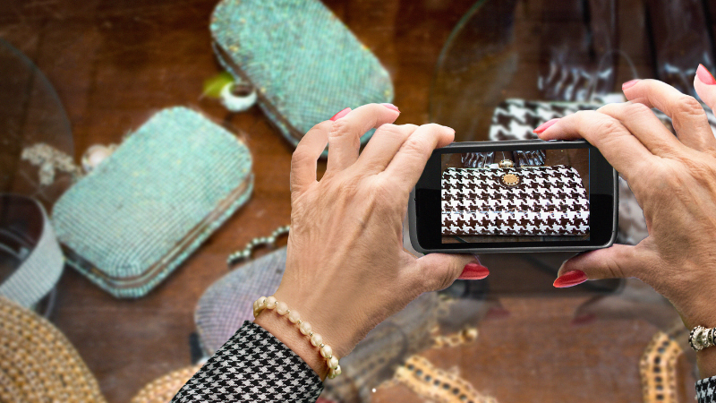 A person taking a picture of a houndstooth purse on a table