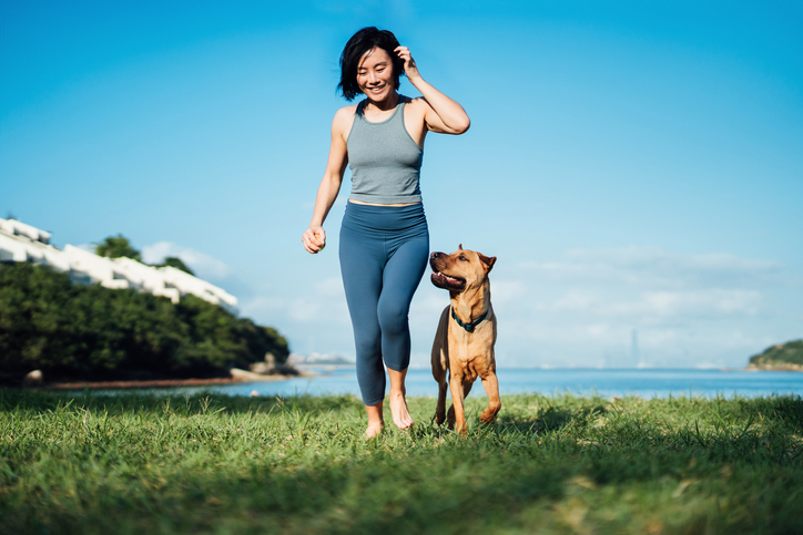 Woman in exercise gear walking with her dog.