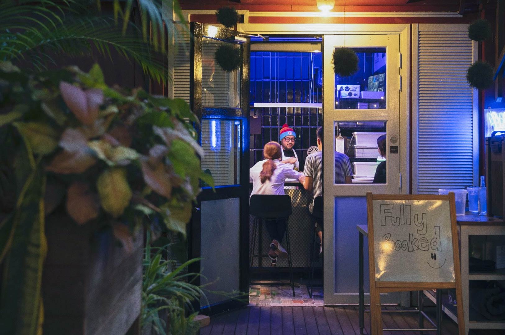 Cozy café interior with customers seated at a counter under warm lighting.
