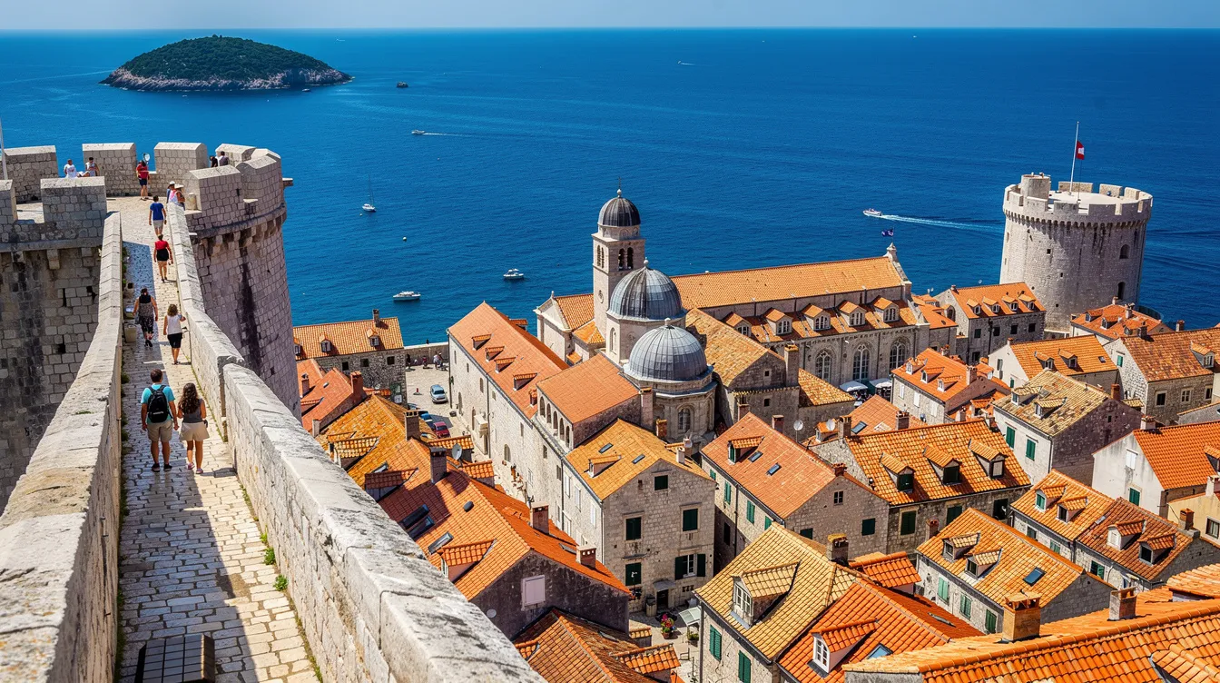 A imagem mostra a bela cidade de Dubrovnik, na Croácia, com suas impressionantes muralhas de pedra à beira do mar Adriático. O cenário inclui o icônico telhado laranja das casas e a vista para o mar, destacando a rica história e cultura da região, que é um popular destino turístico na Europa.