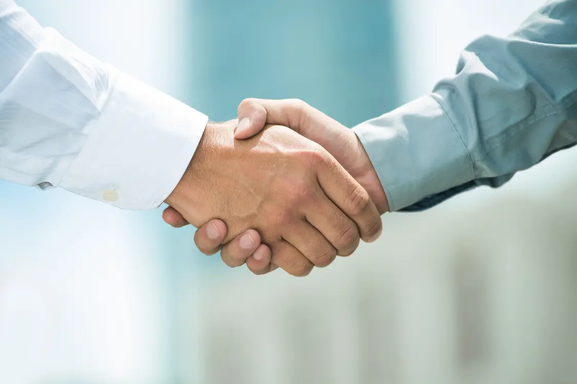 Two professionals shaking hands to represent trust and agreement in remote teams