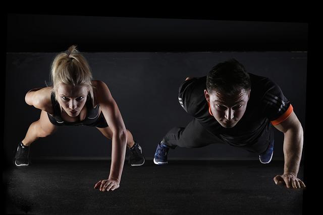 Man and woman performing a one arm push up, attempting to build muscle