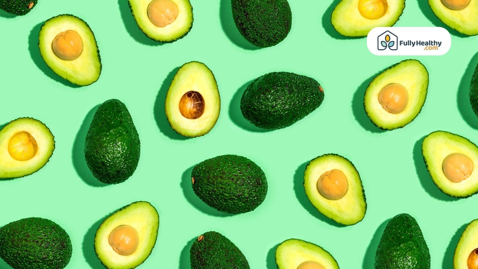 Whole and halved avocados scattered on bright green background surface