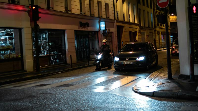 Motorcycle and car stopped at a crosswalk at night