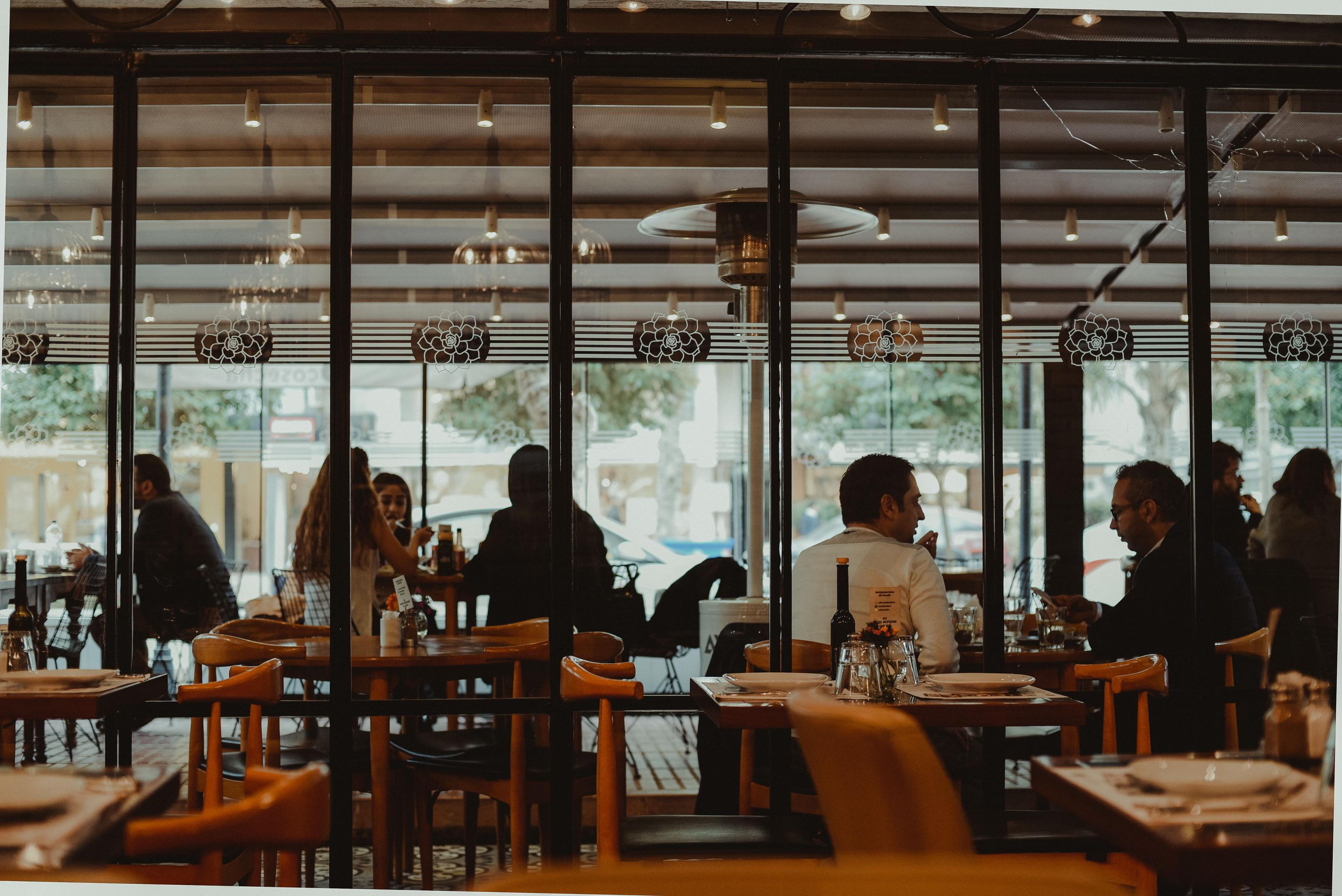 A restaurant manager is intently reviewing sales data on a tablet at the counter, with a coffee cup placed nearby, reflecting the daily operations of a successful restaurant business. This scene highlights the importance of data analysis in improving guest satisfaction and driving restaurant success.
