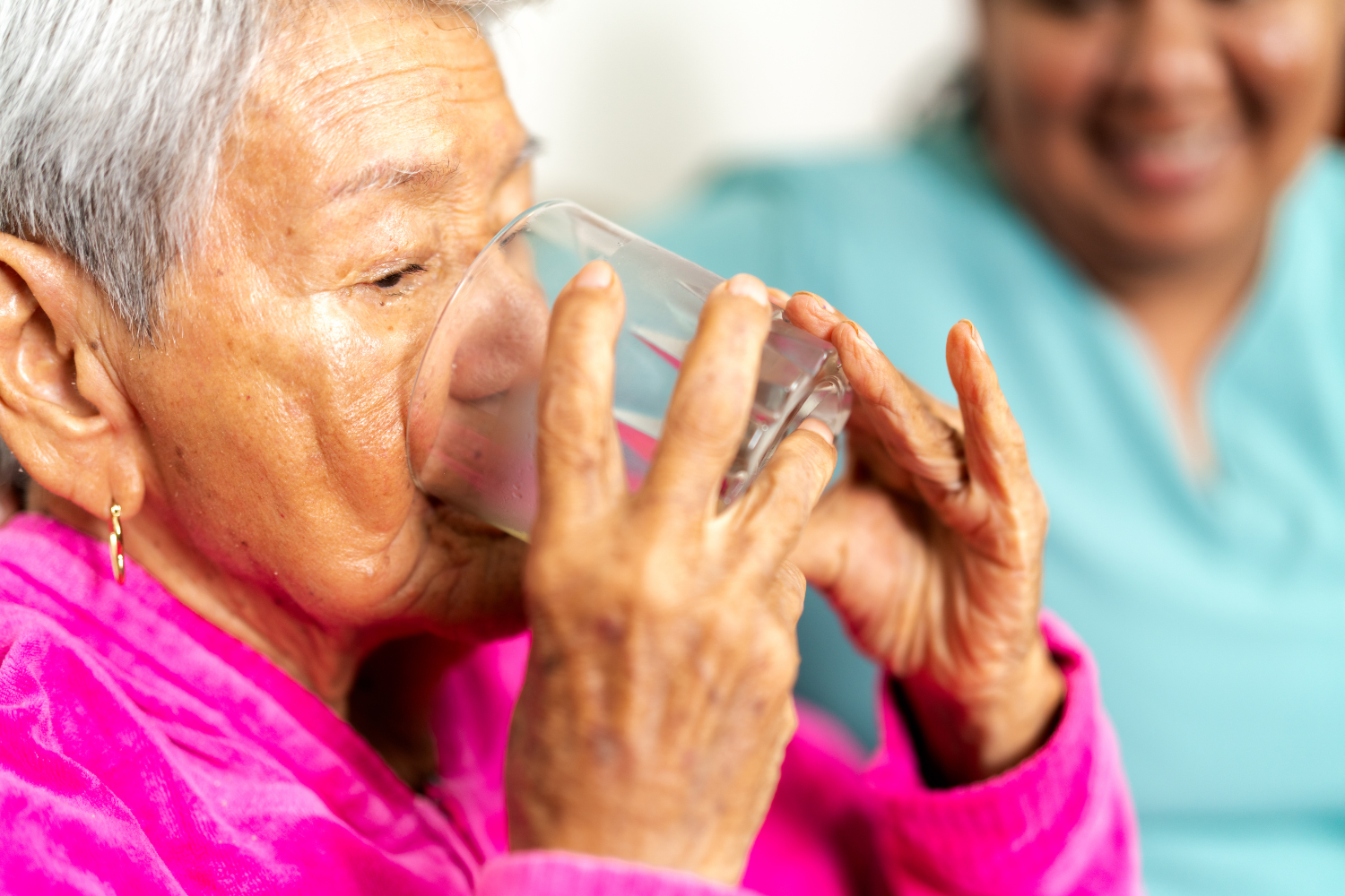 Elderly woman drinking from a glass.