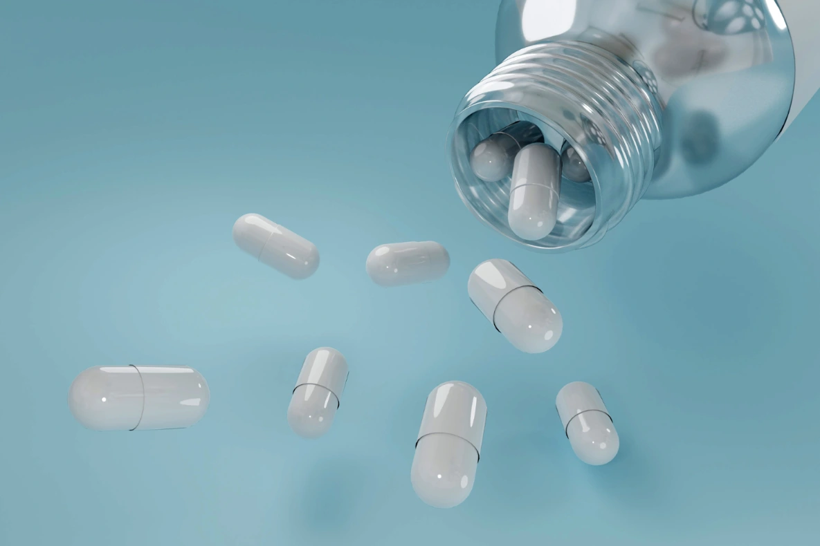 White capsules from a clear bottle against a blue background.