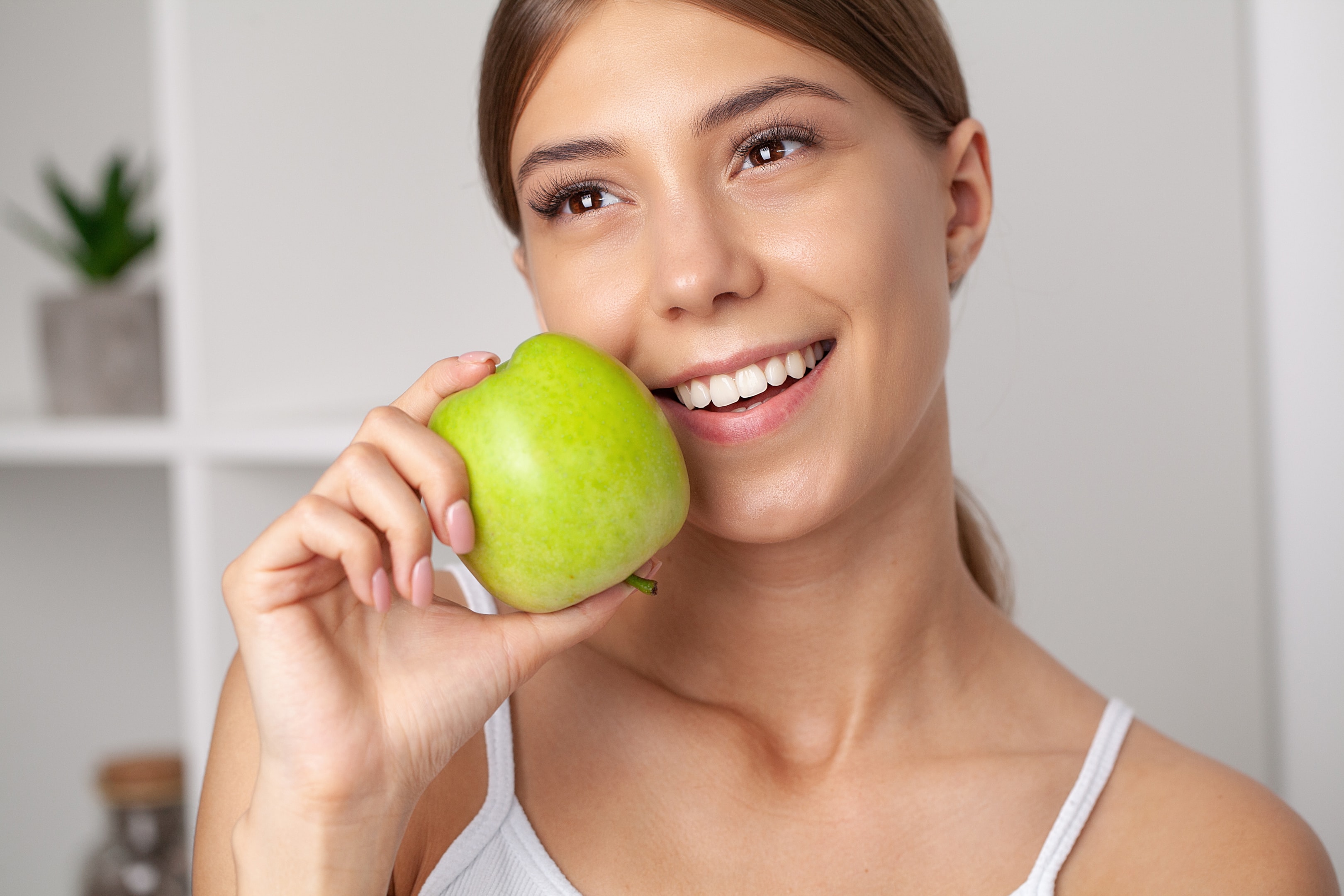 an image of a woman during her first week of healing after surgery and about to eat an apple.