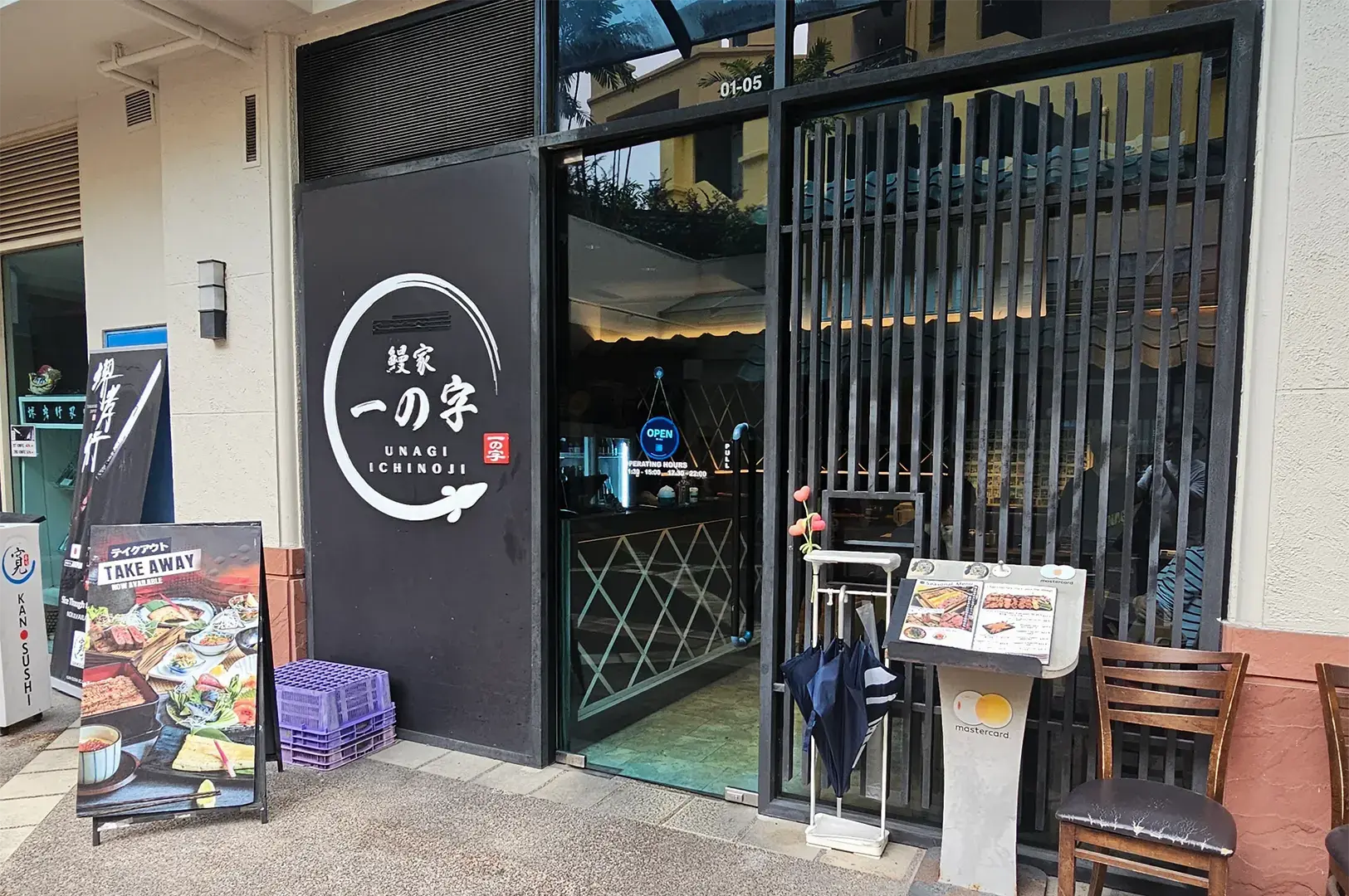 Exterior of Unagi Ichinoji restaurant with slatted wooden decor, glass door entrance, and an outdoor menu display stand.