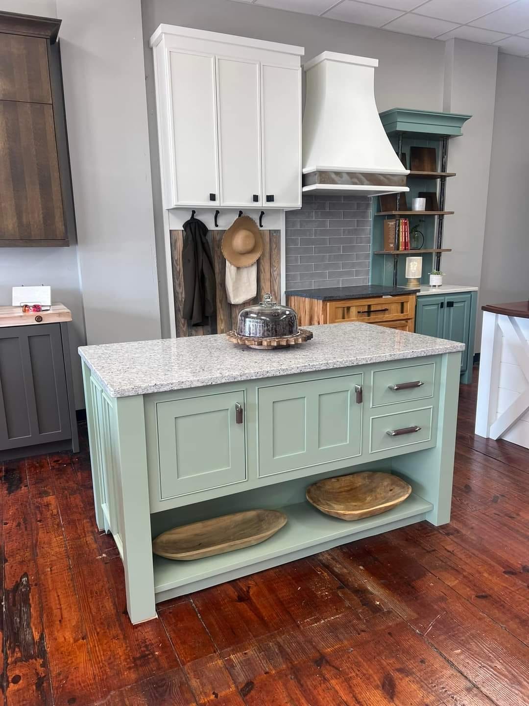 In a modern kitchen showroom, various styles and finishes of kitchen cabinets are displayed, showcasing options for homeowners to create their dream kitchen. The space highlights quality cabinetry and innovative designs, emphasizing customer satisfaction and competitive pricing in Greenville, SC.