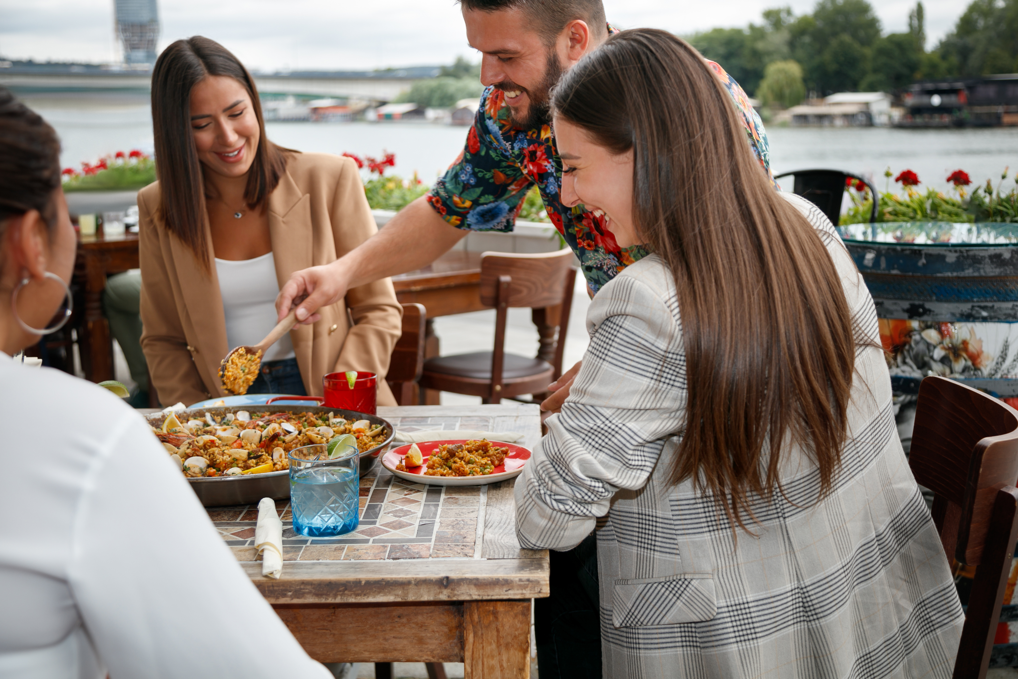 A group of friends having a lunch on an outside terrace next to the water