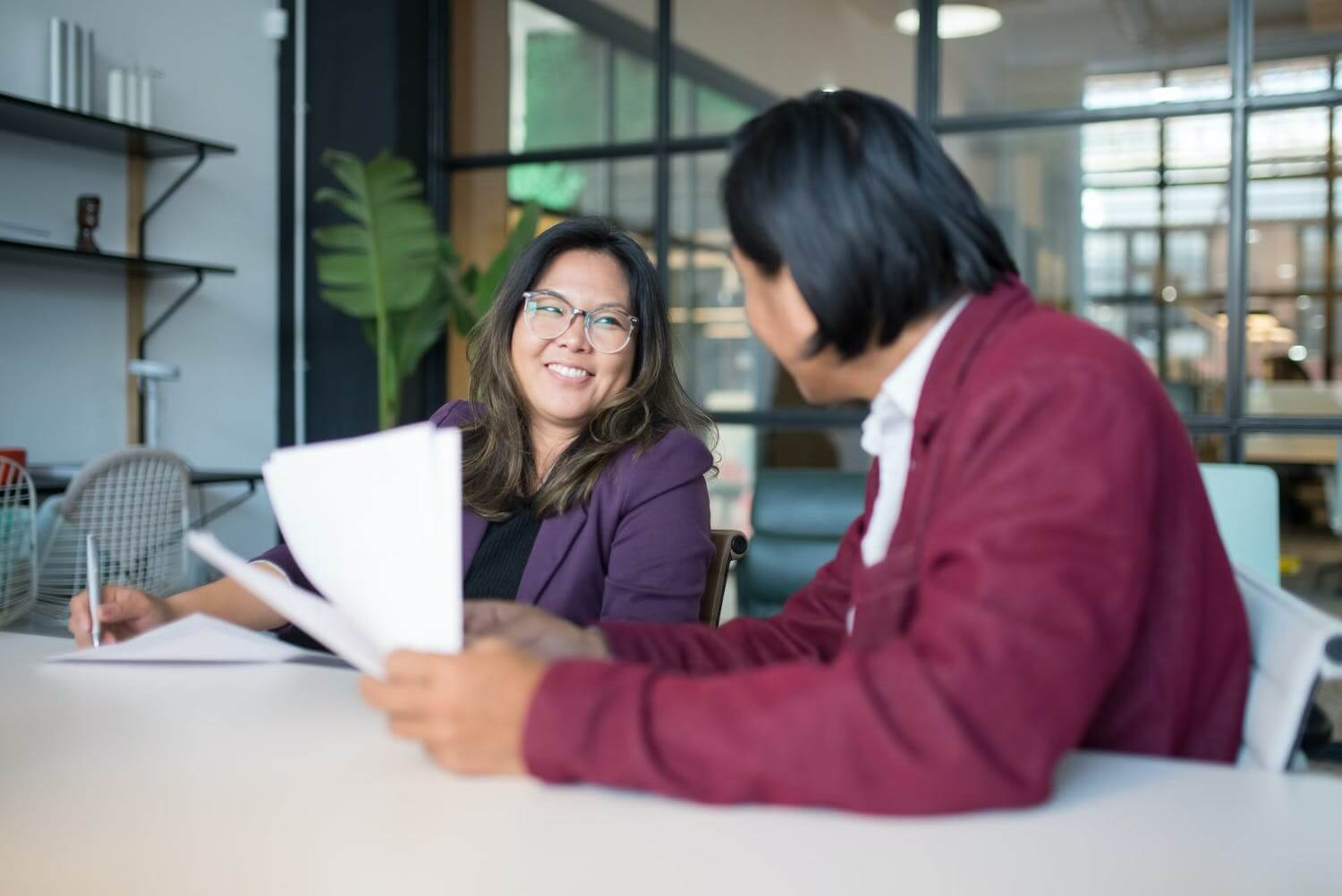 a manager and employee at a desk smiling during a performance review