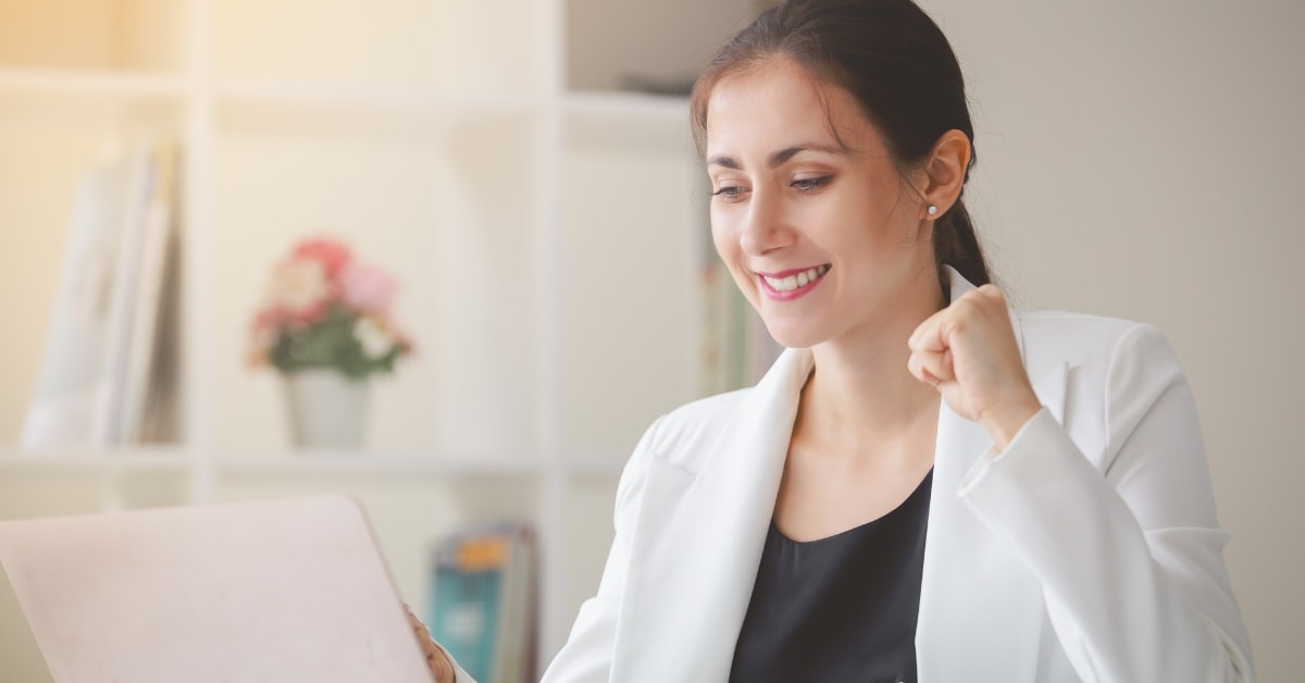 A woman celebrating success while looking at a laptop, highlighting the benefits of expert tax services.