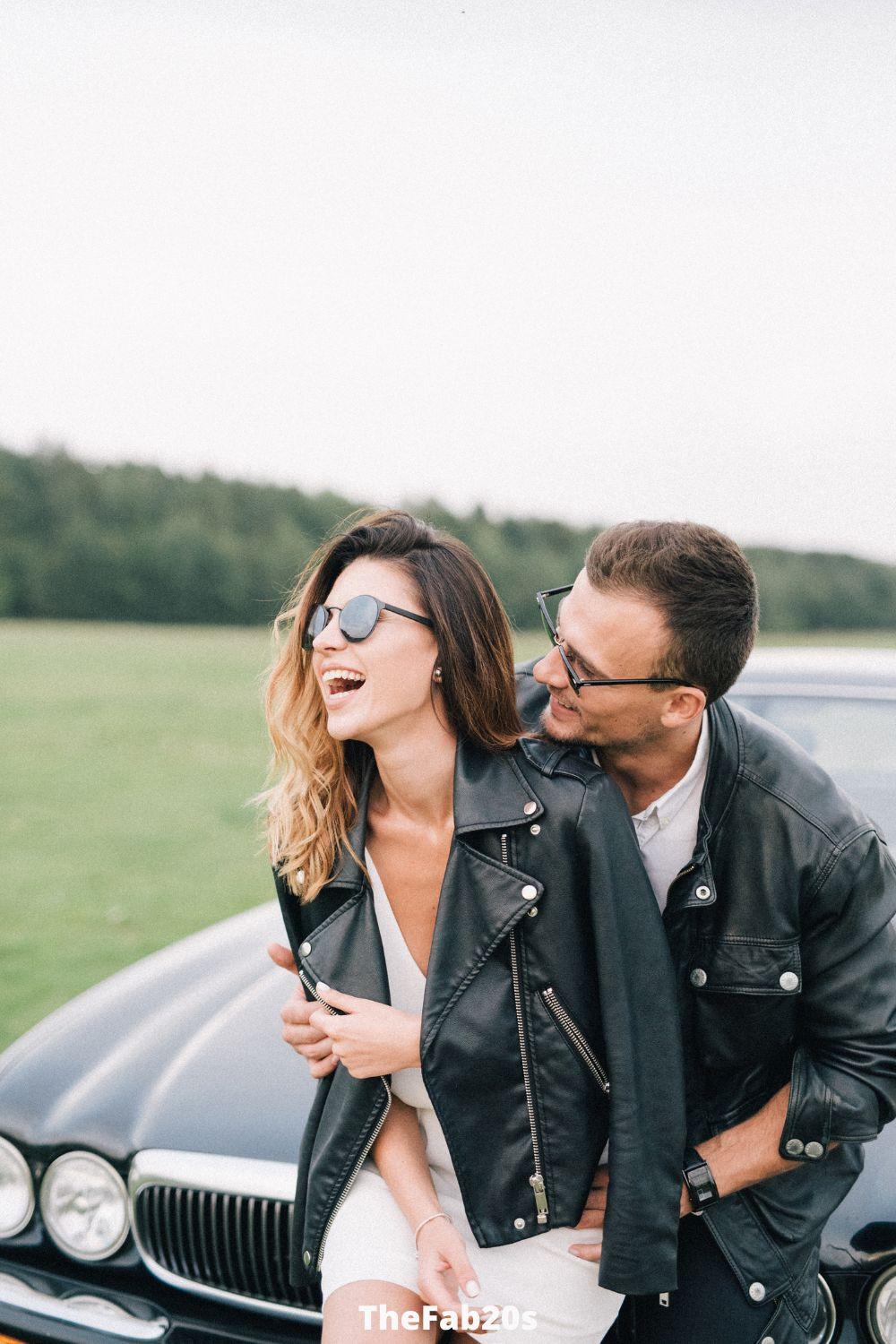 Couple laughing in front of a car 