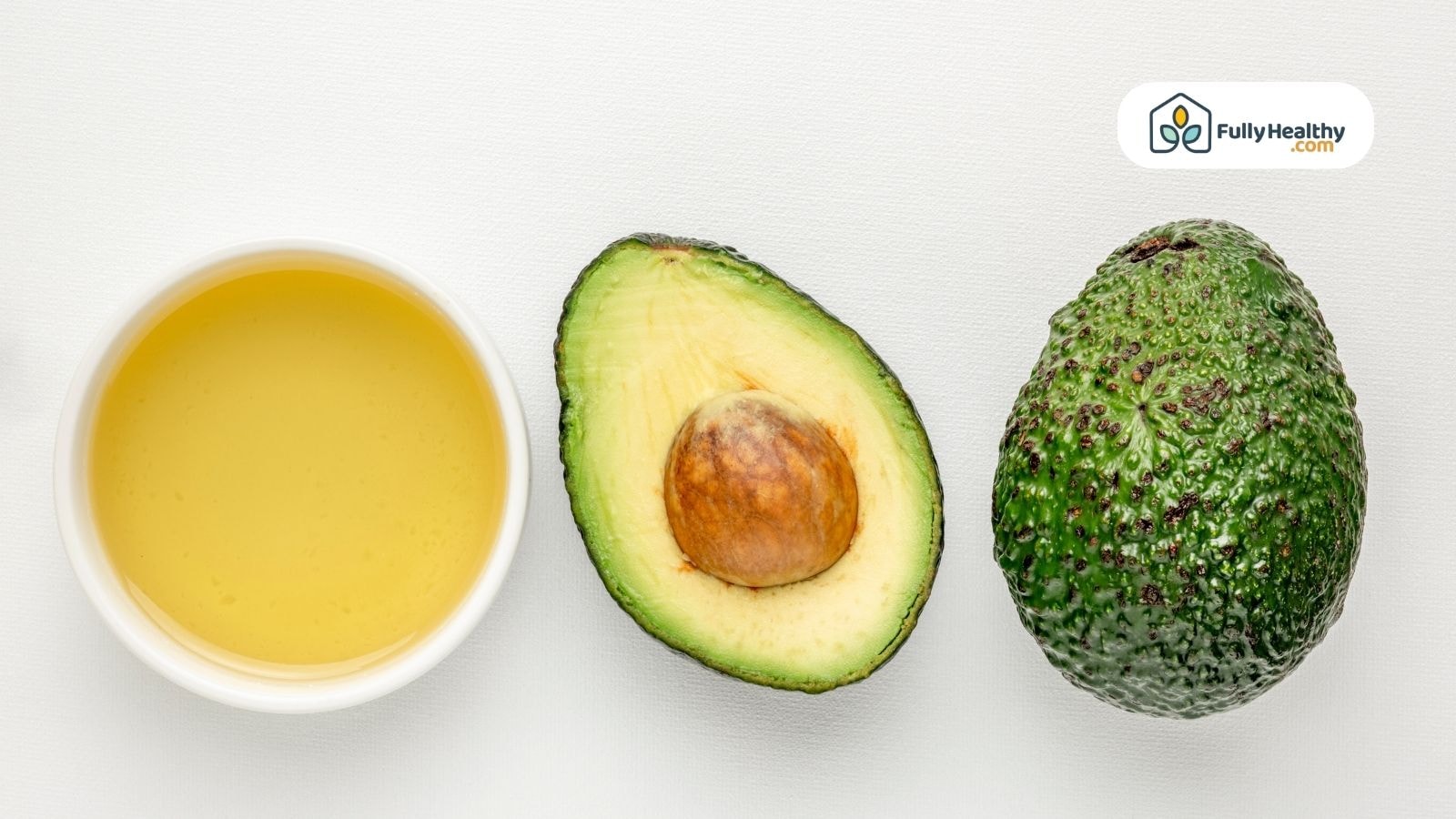 Bowl of avocado oil with fresh whole and halved avocado beside each other