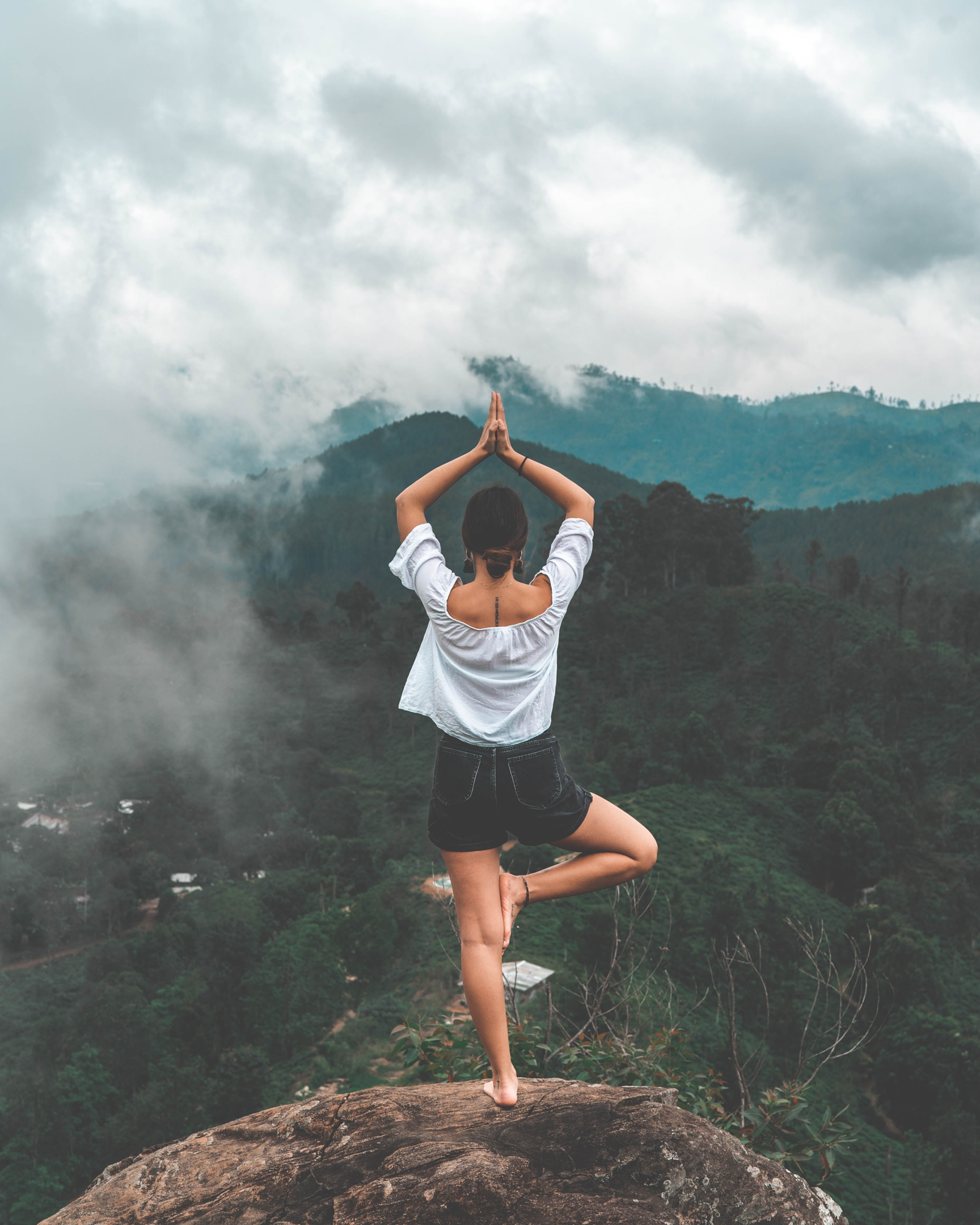 woman standing in yoga tree pose on a mountain 