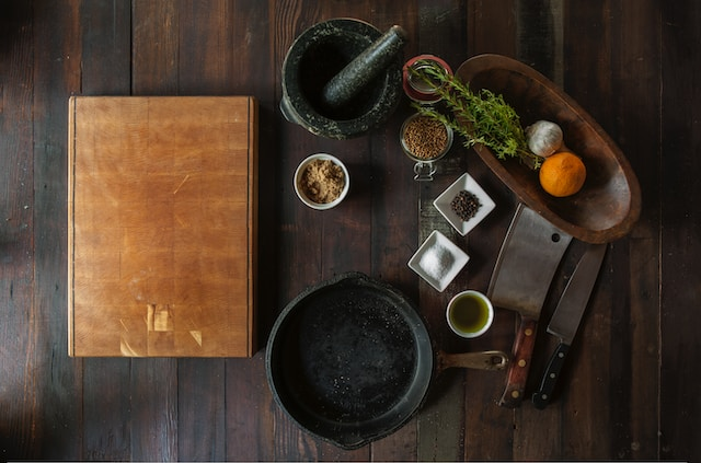 A chefs station with a mixture of bowls and cooking ingredients and utensils on a wooden table