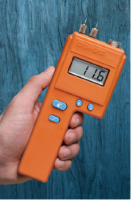 A Delmhorst pinless moisture meter being used to measure the moisture content of a wood surface
