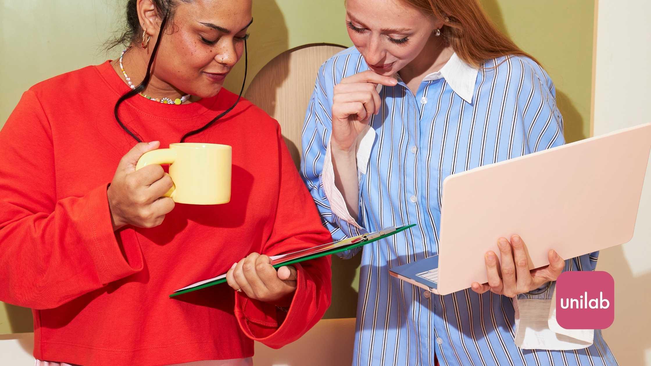 Two women looking at a chart and a laptop