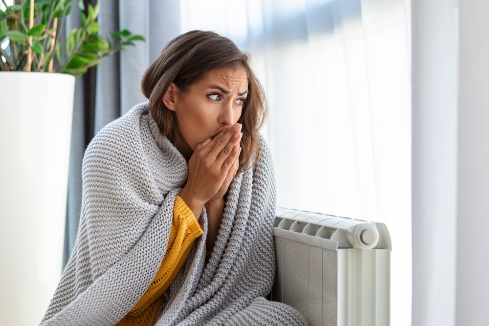 An image showing a person freezing because of an under-sized heating system with too little BTU ratings. 