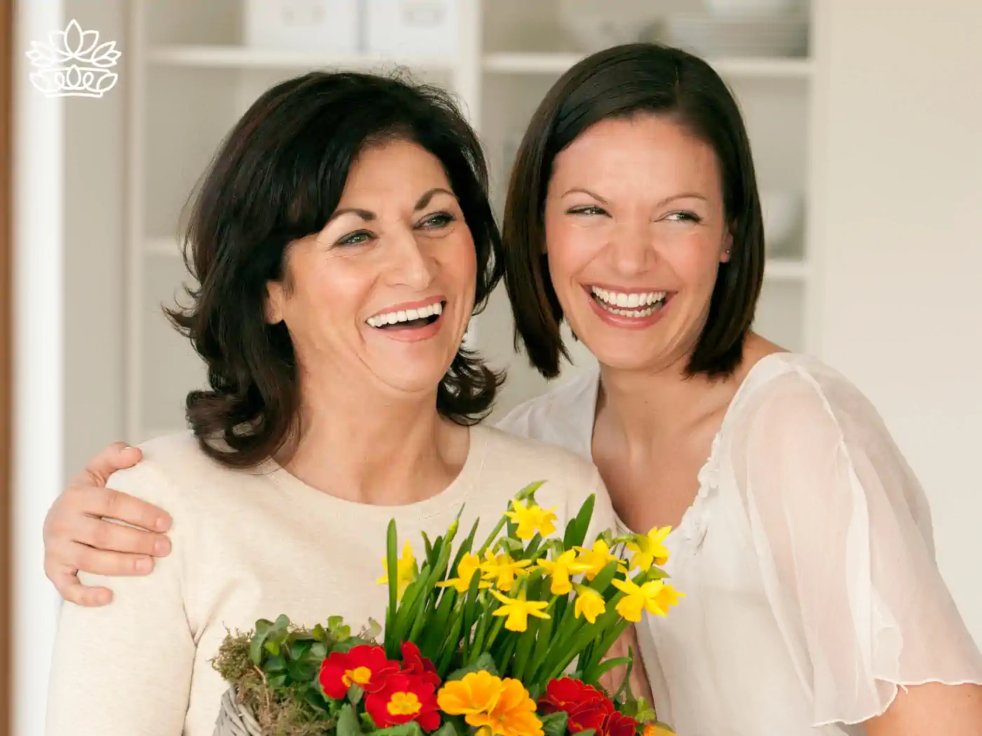 An image of a mother and daughter smiling and holding a colourful arrangement of daffodils and primroses, perfect for expressing love and appreciation. Fabulous Flowers and Gifts.