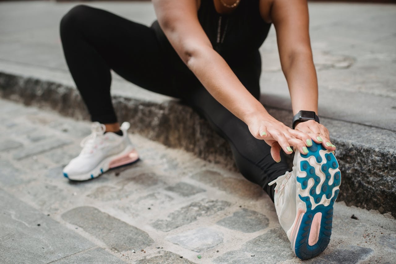 Person stretching leg in running shoes, checking foot discomfort before walking or exercise
