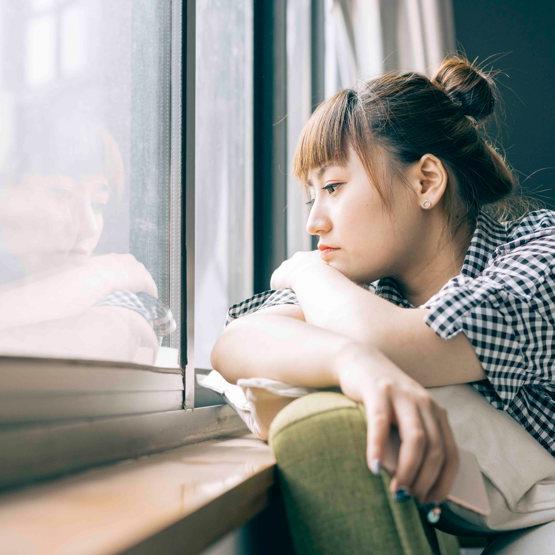 woman looking upset as she looks out of the window