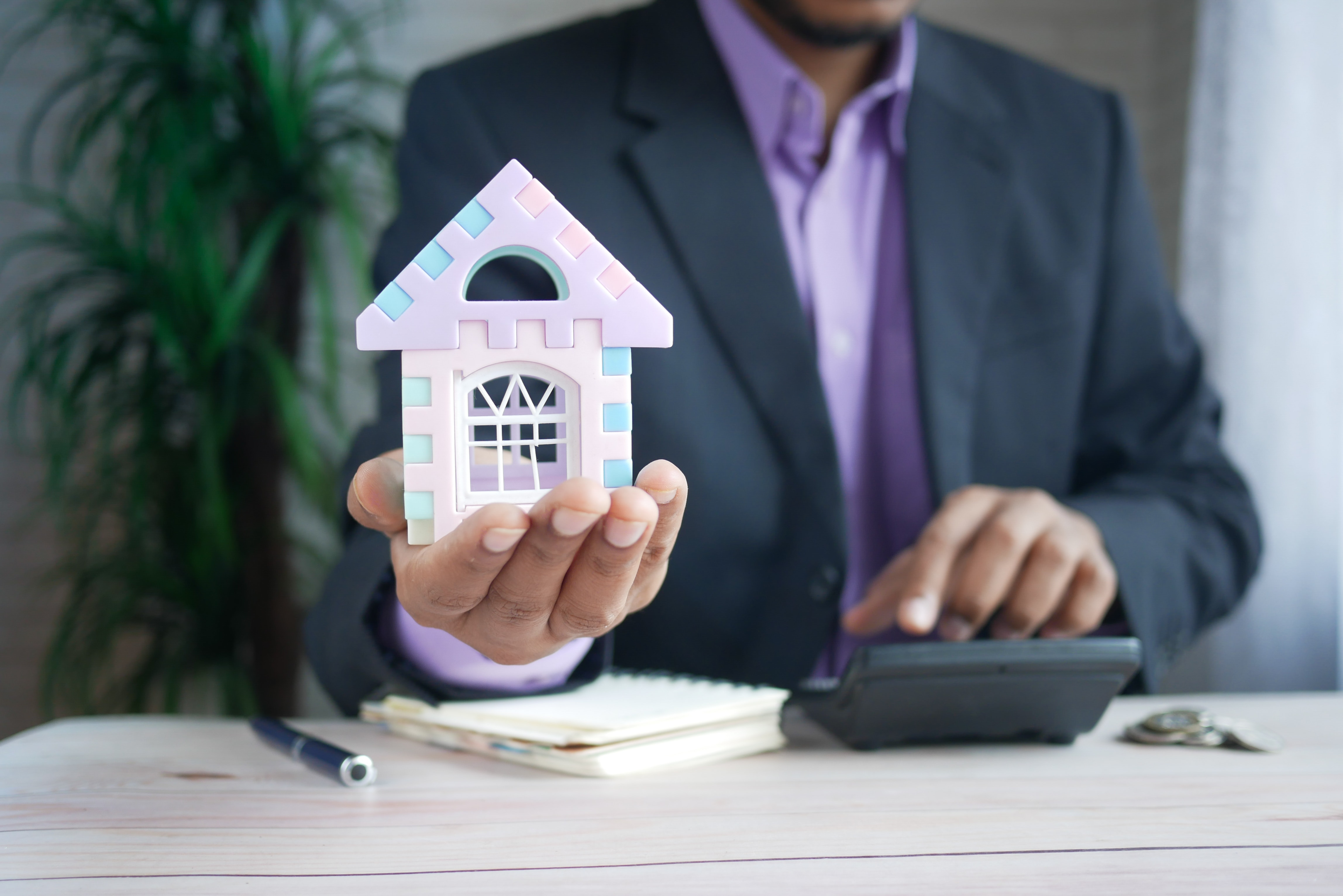 man holding in hand a small plastic multicolored house