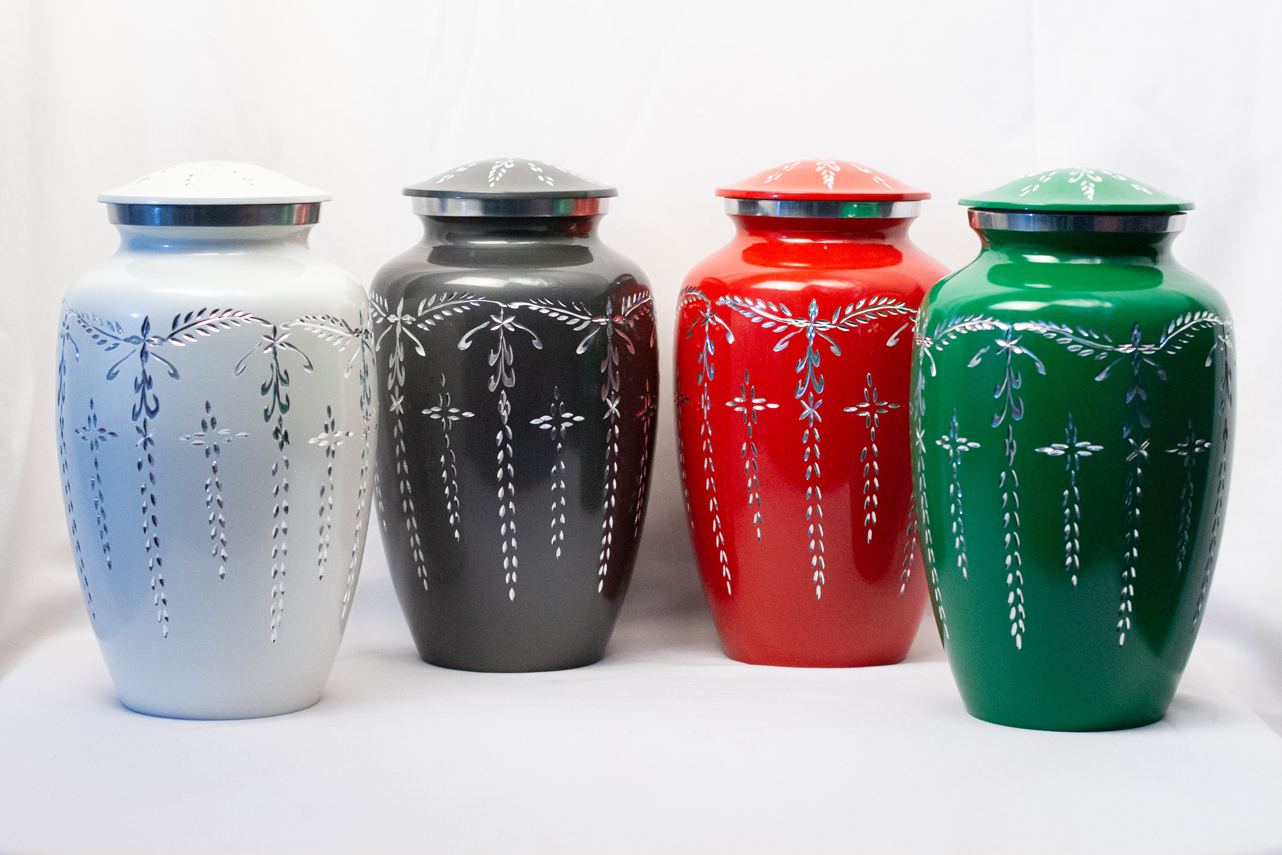 A collection of diamond cut aluminum urns in four different colours by Reverie Memorials