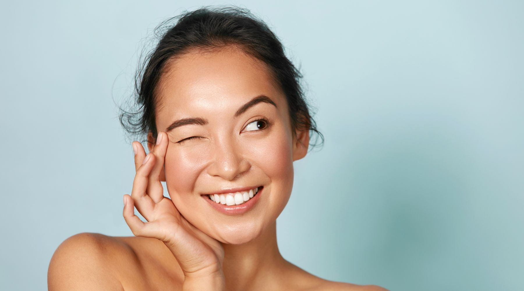 Joyful woman with flawless skin smiling with her eyes closed, expressing satisfaction with skincare results