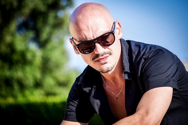Bald man with black shirt, collar, and short sleeves
